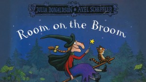 The cover of Room on the Broom showing a witch and her tiger-striped cat riding a broomstick above a forest at night.